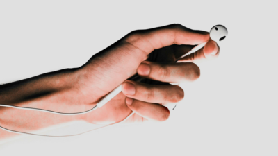 Eine Hand hält Kopfhörer in der Hand – ein Symbol für die wachsende Rolle von KI am Mikrofon und die Zukunft digitaler Audioinhalte.