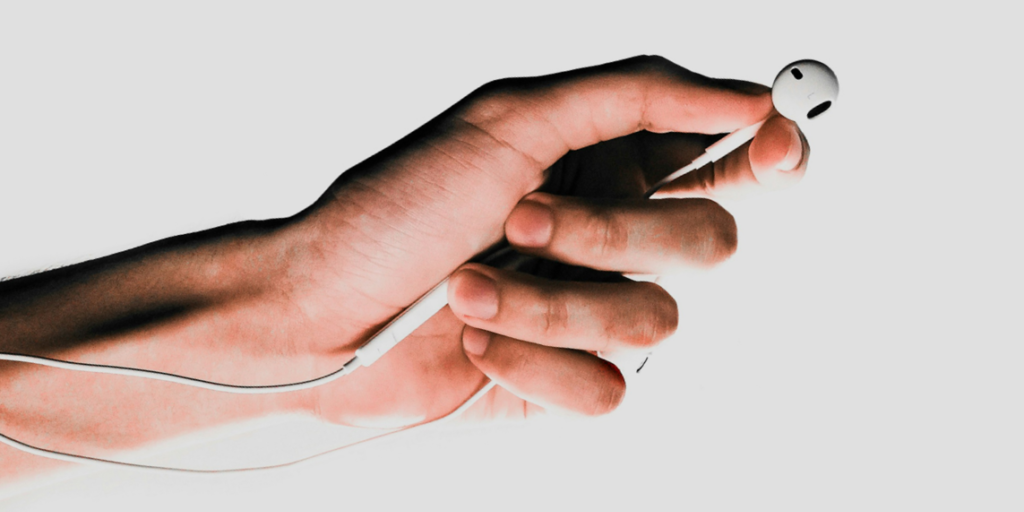 Eine Hand hält Kopfhörer in der Hand – ein Symbol für die wachsende Rolle von KI am Mikrofon und die Zukunft digitaler Audioinhalte.
